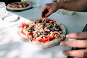 person showing pizza. מסעדות ברומא. אסי מוש 